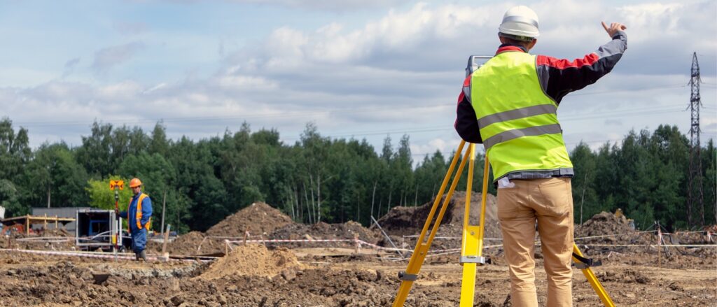 Vermesser mit Tachymeter auf einer Baustelle